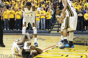 Senior Frantz Massenat grimaces on the floor as his teammates and the DAC pack look on with concern during Drexel’s 93-88 victory over Northeastern University Jan. 11. The point guard played through pain to lead the Dragons to a thrilling double-overtime win.